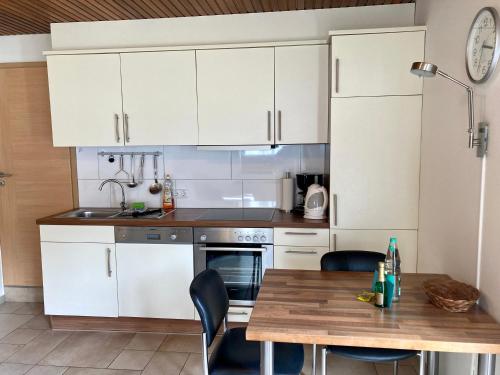 eine Küche mit weißen Schränken und einem Holztisch in der Unterkunft Haus Wilhelmi Wilhelmi Whg 4 in Wangerooge
