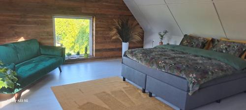 een slaapkamer met een bed, een bank en een raam bij B & B Meerland43 in Meerland