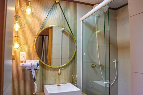 a bathroom with a shower and a sink and a mirror at Hotel da Inês in Visconde De Maua