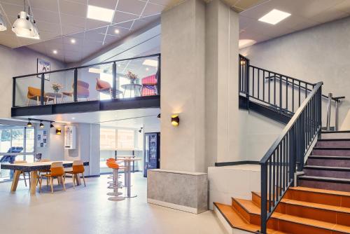a lobby with stairs and a table and chairs at ibis budget Paris Porte d'Aubervilliers in Aubervilliers