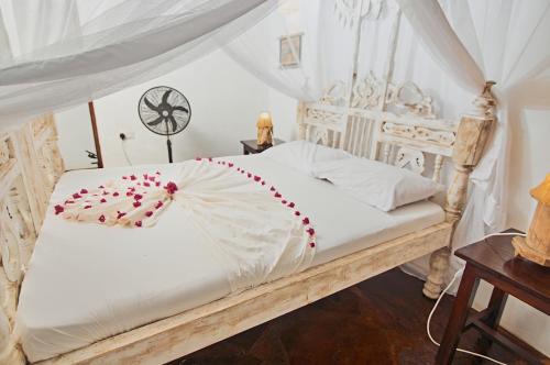 a bedroom with a white bed with a white canopy at Mvuvi Lodge in Watamu