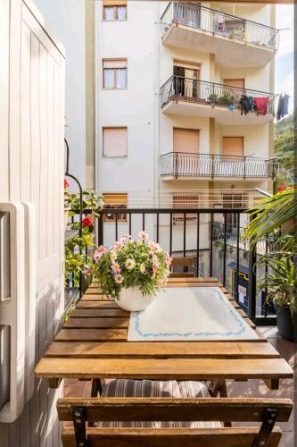 a balcony with a wooden table and flowers on it at Camera privata nell'appartamento in zona residenziale con 2 piscine in Rapallo