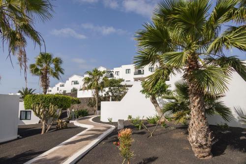 una palmera frente a un edificio blanco en ILUNION Costa Sal Lanzarote en Puerto del Carmen