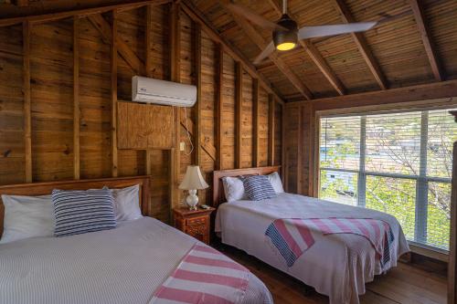 two beds in a room with wooden walls at Ocean Breeze Villa Rentals in Oak Ridge