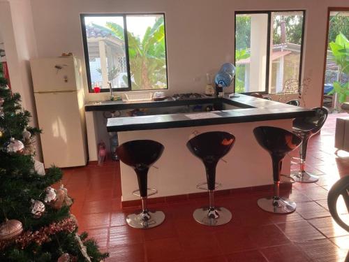 a kitchen with a counter with four bar stools at Casa finca La alegría - casa el Recreo in La Mesa