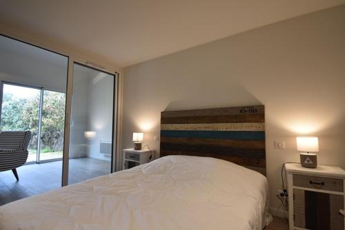 - une chambre avec un lit blanc et une porte coulissante en verre dans l'établissement Maisonnette - Hossegor agréable maisonnette entre lac et océan, à Soorts-Hossegor