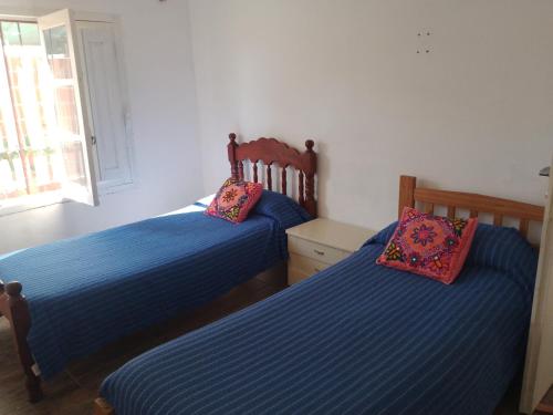 2 camas en un dormitorio con sábanas azules y almohadas rosas en Como en casa en Gualeguaychú
