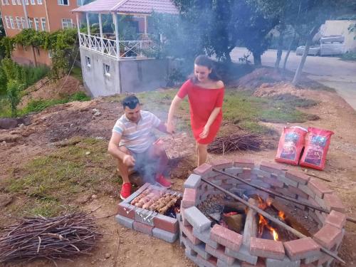 a woman standing next to a man next to a fire at Daiana's home in Gegelidzeebi