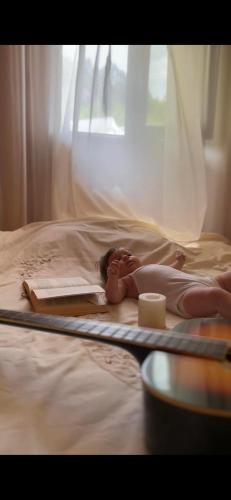 a baby laying on a bed with a book at Daiana's home in Gegelidzeebi