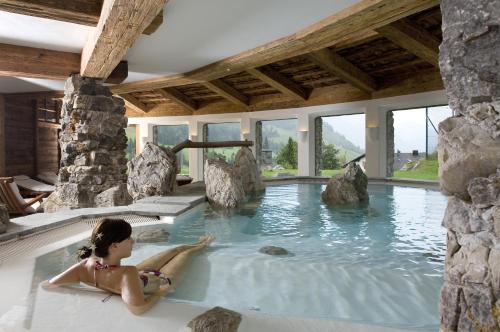a woman laying in a hot tub in a house at LANIG Hotel Resort&Spa - Wellness und Feinschmeckerhotel - family owned and managed in Oberjoch