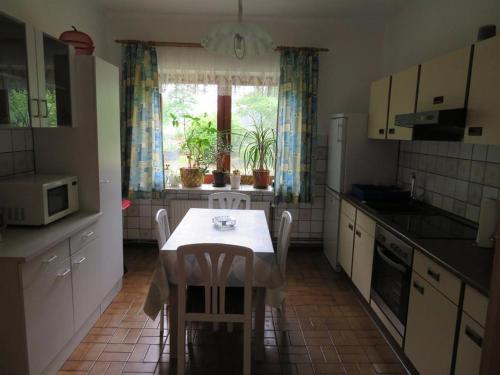 una cocina con una mesa y sillas blancas y una ventana en Timmerloher Weg, Ferienwohnung, en Schneverdingen