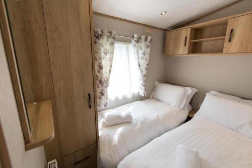 Habitación pequeña con 2 camas y ventana en Mallard Lake, en South Cerney
