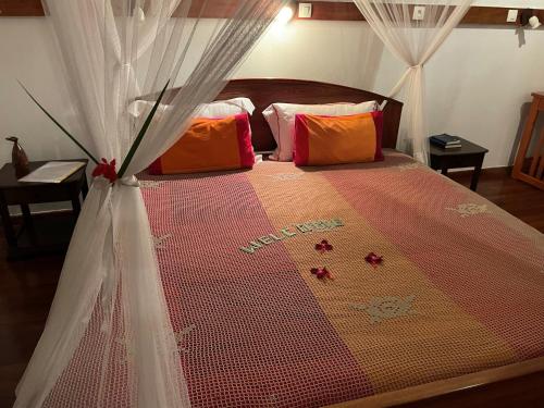 a bedroom with a bed with red and orange pillows at Hotel Ambalakely in Ambalakely