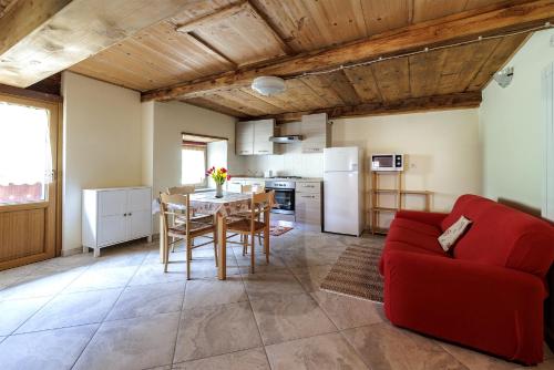 a kitchen and living room with a red couch and a table at La WalserHus in Formazza