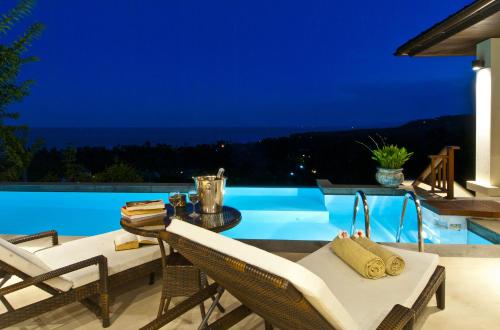a patio with chairs and a pool at night at Villa Baan Saitara in Lamai