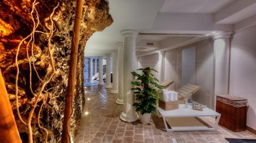 a hallway with white columns and a plant at Hotel Plaza in Porto Azzurro