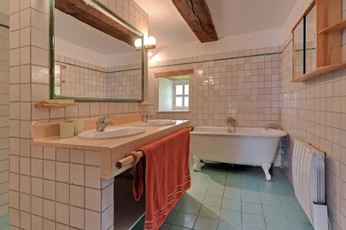 a bathroom with two sinks and a tub and a mirror at Le Moulin neuf in Alexain
