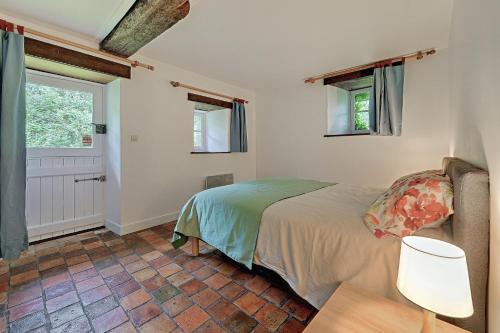 a bedroom with a bed and a table and windows at Le Moulin neuf in Alexain