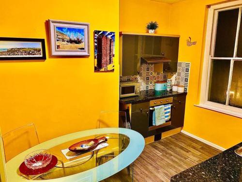 a yellow kitchen with a glass table in a room at Apartment in Old Town near the beach in Hastings