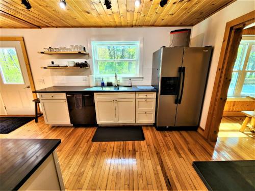 a kitchen with a stainless steel refrigerator and wooden floors at 3 Cottage Exclusive Retreat-Hot Tubs-Walk to Beach in Traverse City