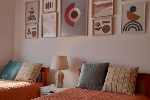 a bedroom with two beds and pictures on the wall at Mar Doce Lar- Entre Mar e Ria in Gafanha da Nazaré