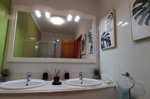 a bathroom with two sinks and a large mirror at Mar Doce Lar- Entre Mar e Ria in Gafanha da Nazaré