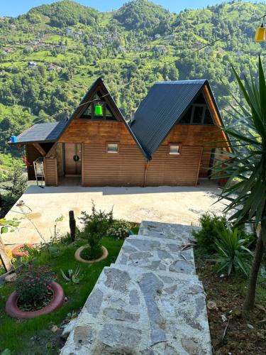 a large wooden house with a mountain in the background at Soore Bungalov in Ardeşen