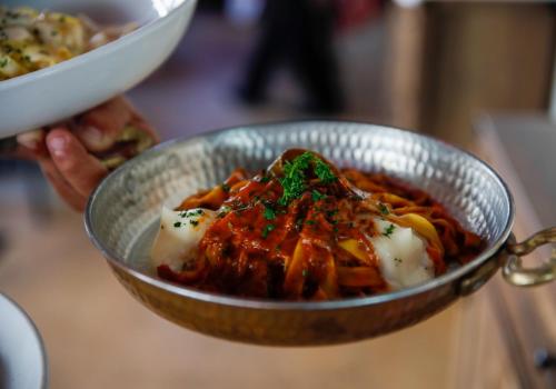 a person holding a bowl of pasta with sauce at Ocean Reef Suites in Miami Beach