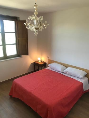 a bedroom with a red bed with a chandelier at Agriturismo Poggio Ajano in Abbazia di Santa Maria in Selva