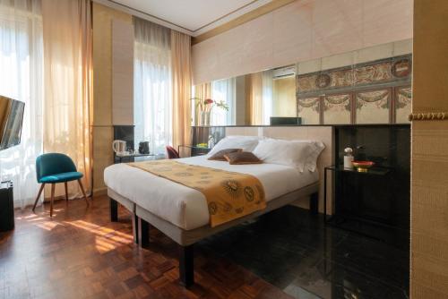 a bedroom with a large bed and a blue chair at Rivière Private Rooms Alla Scala in Milan