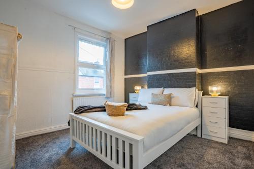 a bedroom with a white bed with a black headboard at STAYZED G - Edge Of Nottingham City Centre NG7, Great Amenities & Transport Links - Ideal for Short & Long Stays in Nottingham
