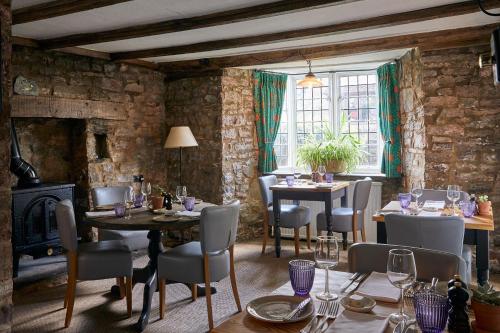a dining room with tables and chairs and a fireplace at Tudor Farmhouse Hotel in Clearwell