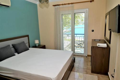 a bedroom with a large white bed and a balcony at Marianna Appartaments in Plataria