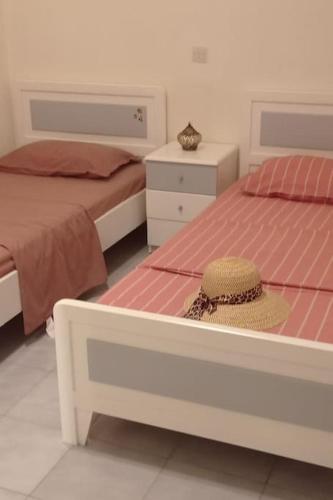 a bedroom with two beds with a hat sitting on it at Sophie's Summer House in Nea Fokea