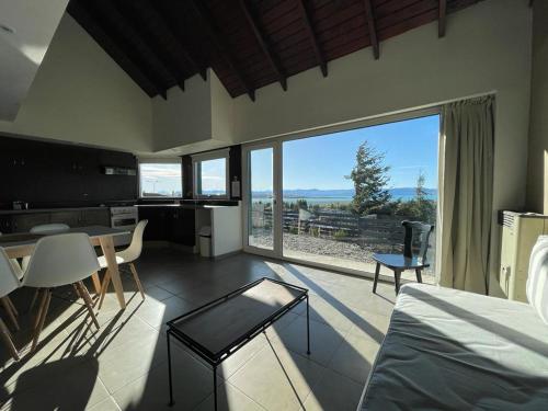 a living room with a table and a large window at MI CASA TU CASA in El Calafate
