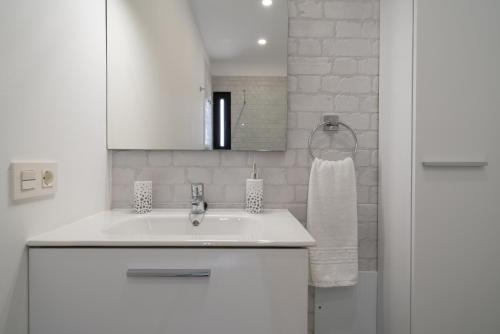 Un baño blanco con lavabo y espejo. en Sabbia Suites My Place, en La Santa