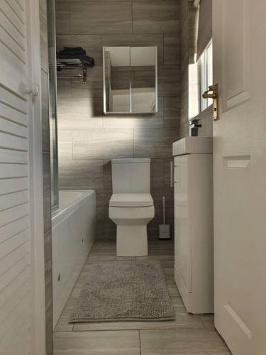 a bathroom with a toilet and a tub and a mirror at Awave From It All - Escape the city life in Jaywick Sands