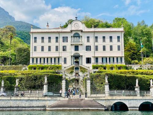 a large building with a bridge in front of a body of water at La casa al lago BMOR love&lake in Mezzegra
