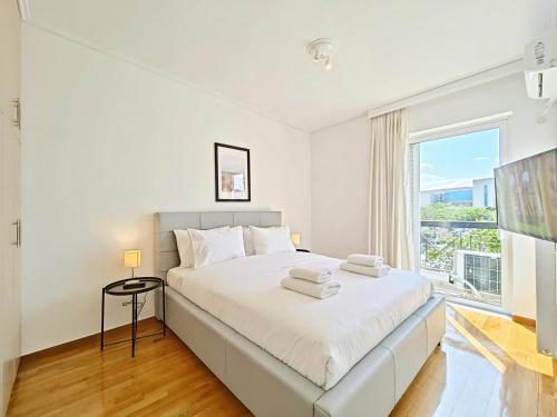 a white bedroom with a large bed and a window at Menelaou by Verde Apartments in Athens