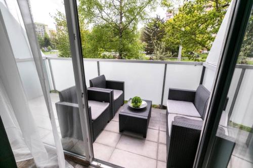 einen Balkon mit 2 Stühlen und einem Tisch mit einer Pflanze in der Unterkunft ALURE RESIDENCES 1 & 24h self check-in, free parking in front of the apartment building, new building, terrace, cafe with breakfast in the apartment building, next to the aqua park in Banská Bystrica