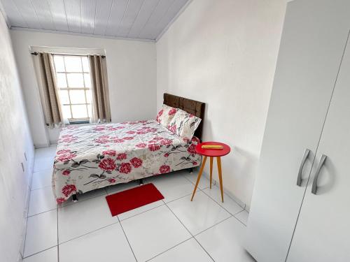 a small bedroom with a bed and a red stool at São Francisco Aparts in Salvador