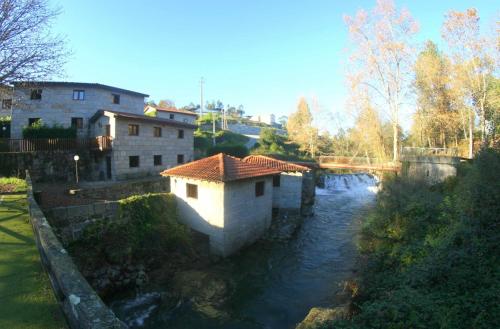 a bridge over a river with a house on it at Rilhadas Casas de Campo in Fafe