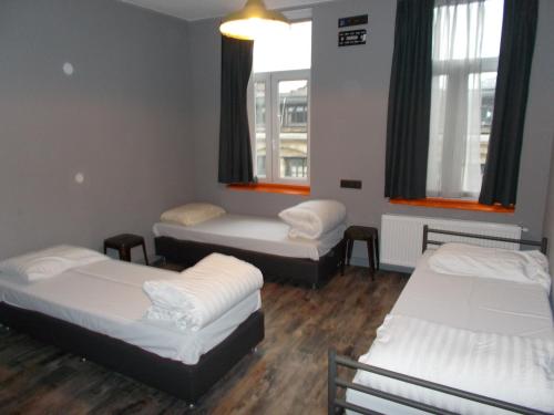 a room with three beds and two windows at Urban City Centre Hostel in Brussels
