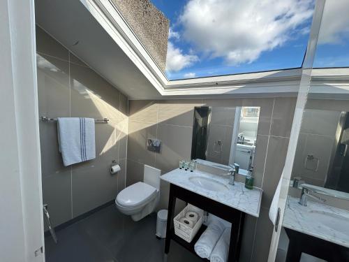 a bathroom with a toilet and a sink and a window at Sun Street Aparthotel in Lancaster