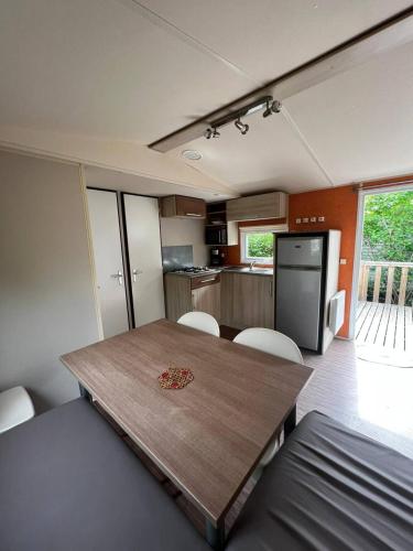 une cuisine et une salle à manger avec une table et des chaises en bois dans l'établissement Mobil Home Cosi Climatisé pour 6 - Camping Tohapi, à Vogelgrun