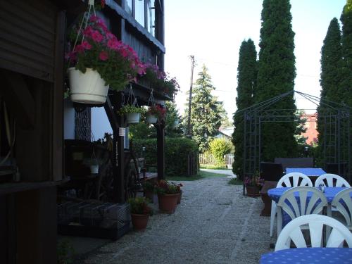a patio with white chairs and tables and flowers at Krisztina Panzió in Balatonalmádi