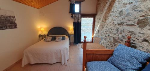 a bedroom with a bed and a couch and a stone wall at Chambres d'hôtes les Hautes Papinières in Saint-Prouant