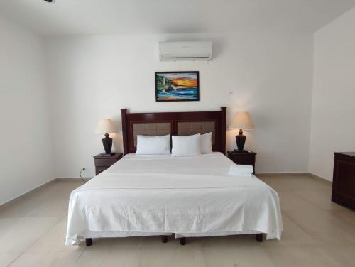 a bedroom with a large white bed with two lamps at Casa Chelem in Chelem