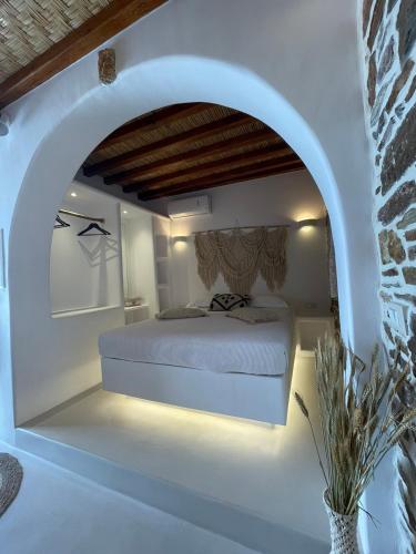 biała sypialnia z łóżkiem w łuku w obiekcie Psathi w mieście Kitnos