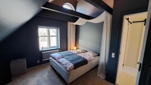 een slaapkamer met een bed met blauwe muren en een raam bij Guesthouse Gärsnäs in Gärsnäs
